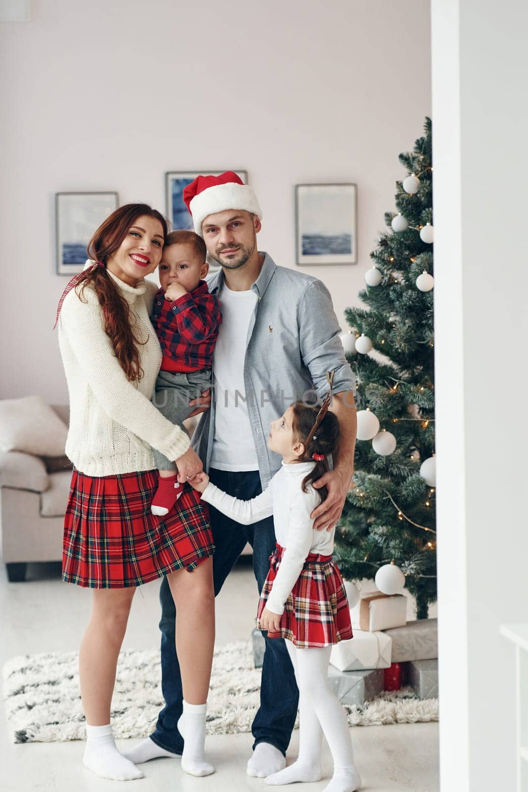 Standing together. Beautiful family celebrates New year and christmas indoors at home by Standret