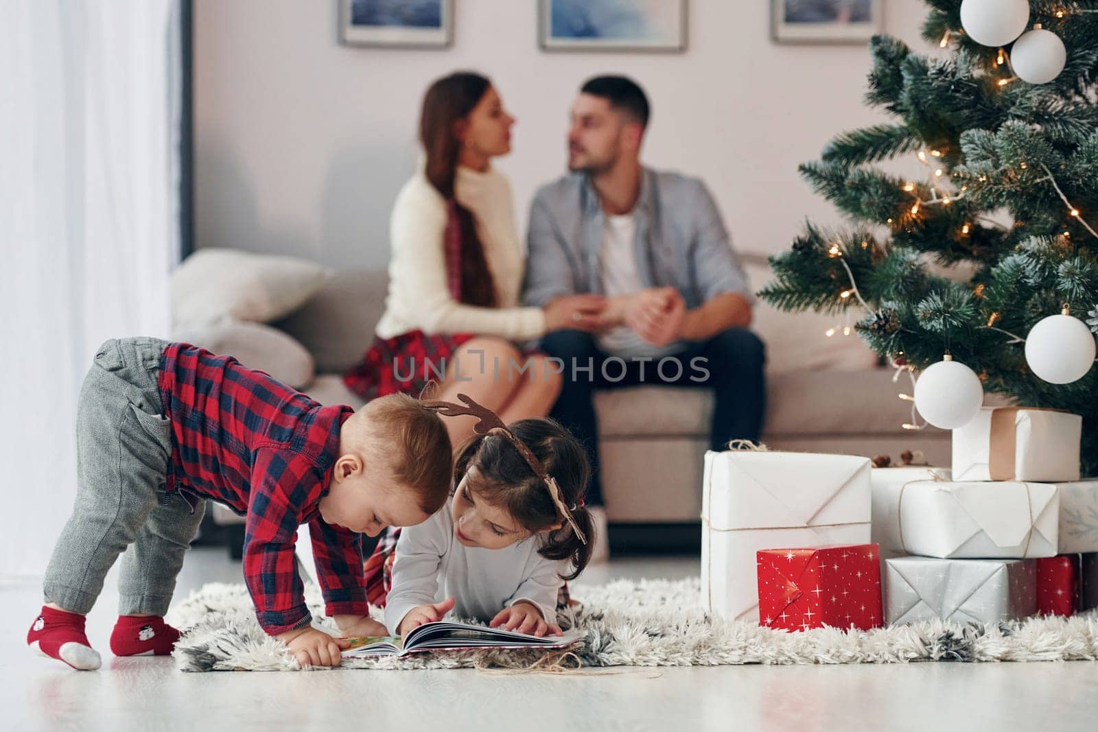 Sister and brother have fun. Beautiful family celebrates New year and christmas indoors at home by Standret