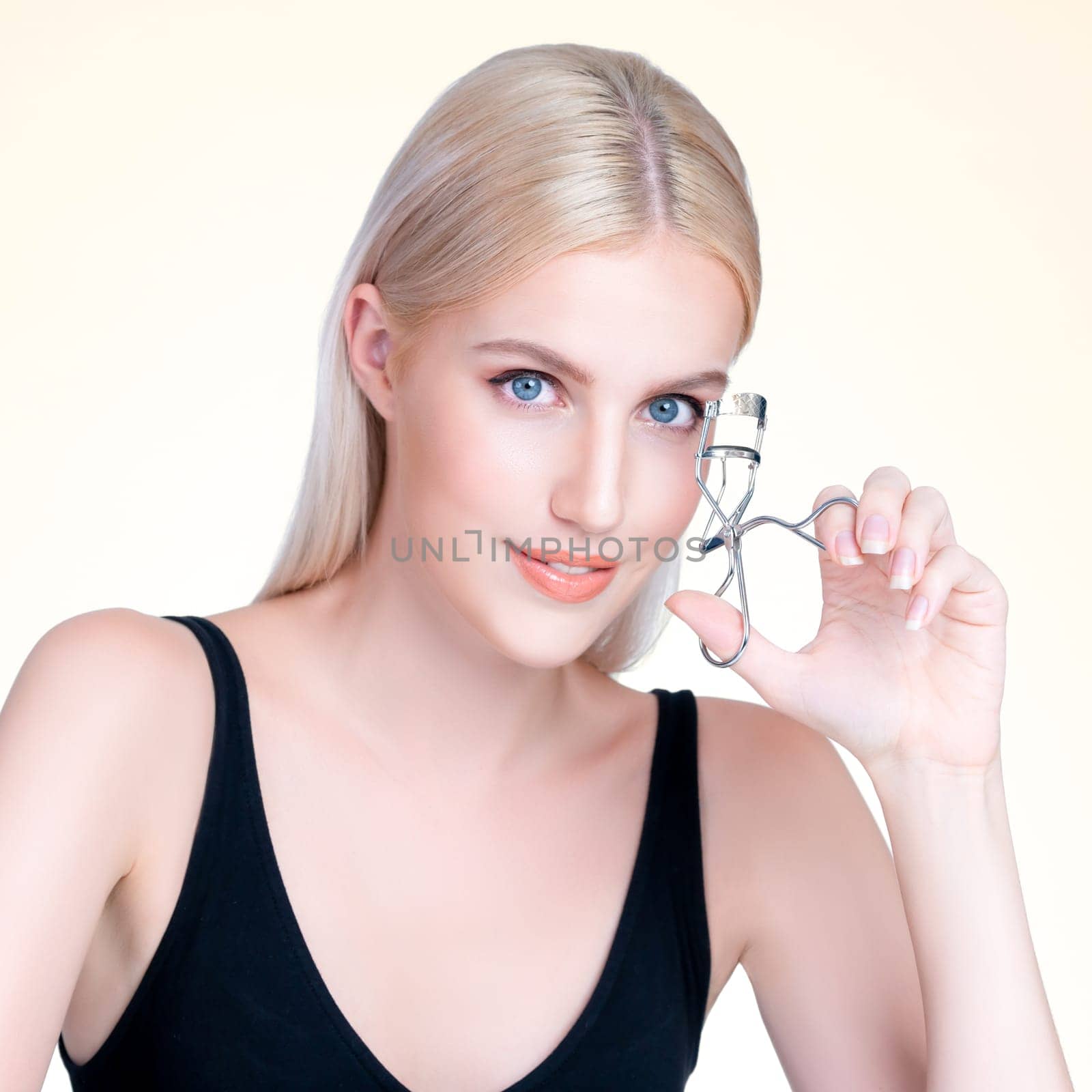 Personable woman correct eyelash curler with alluring facial makeup by biancoblue