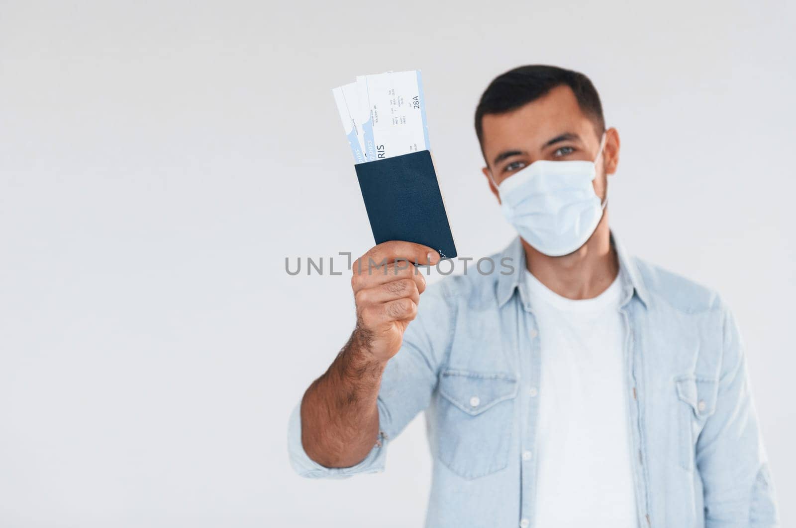 Tourist with ticket. Young handsome man standing indoors against white background.