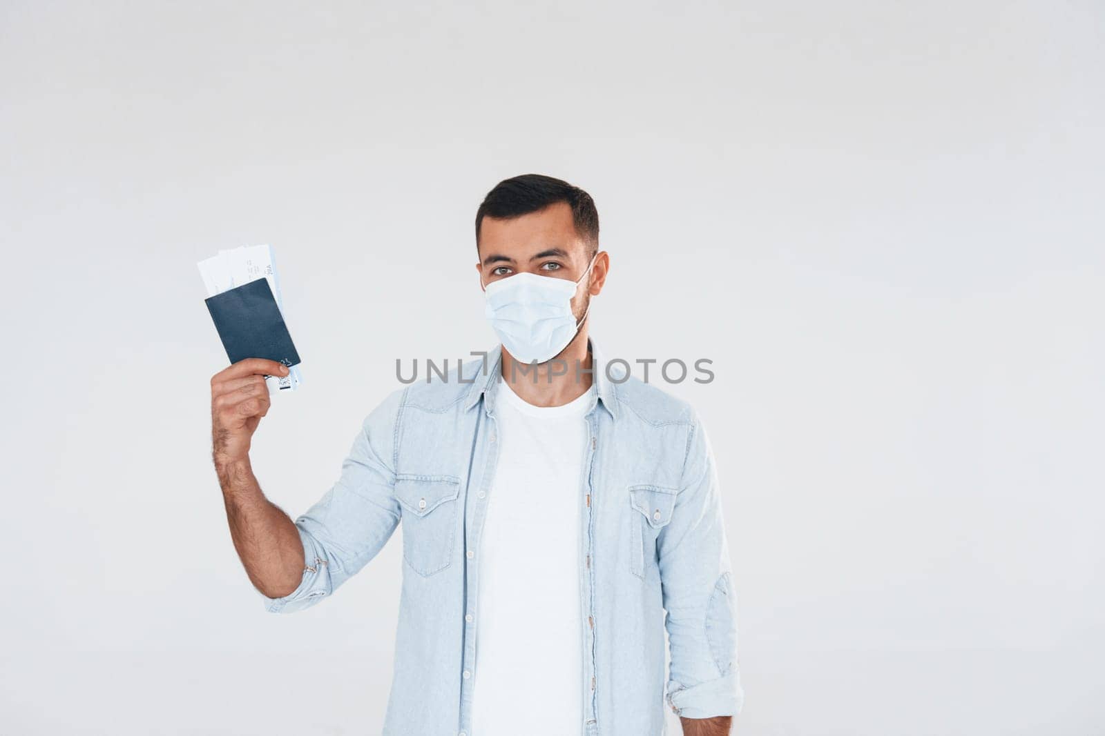 Tourist with ticket. Young handsome man standing indoors against white background.