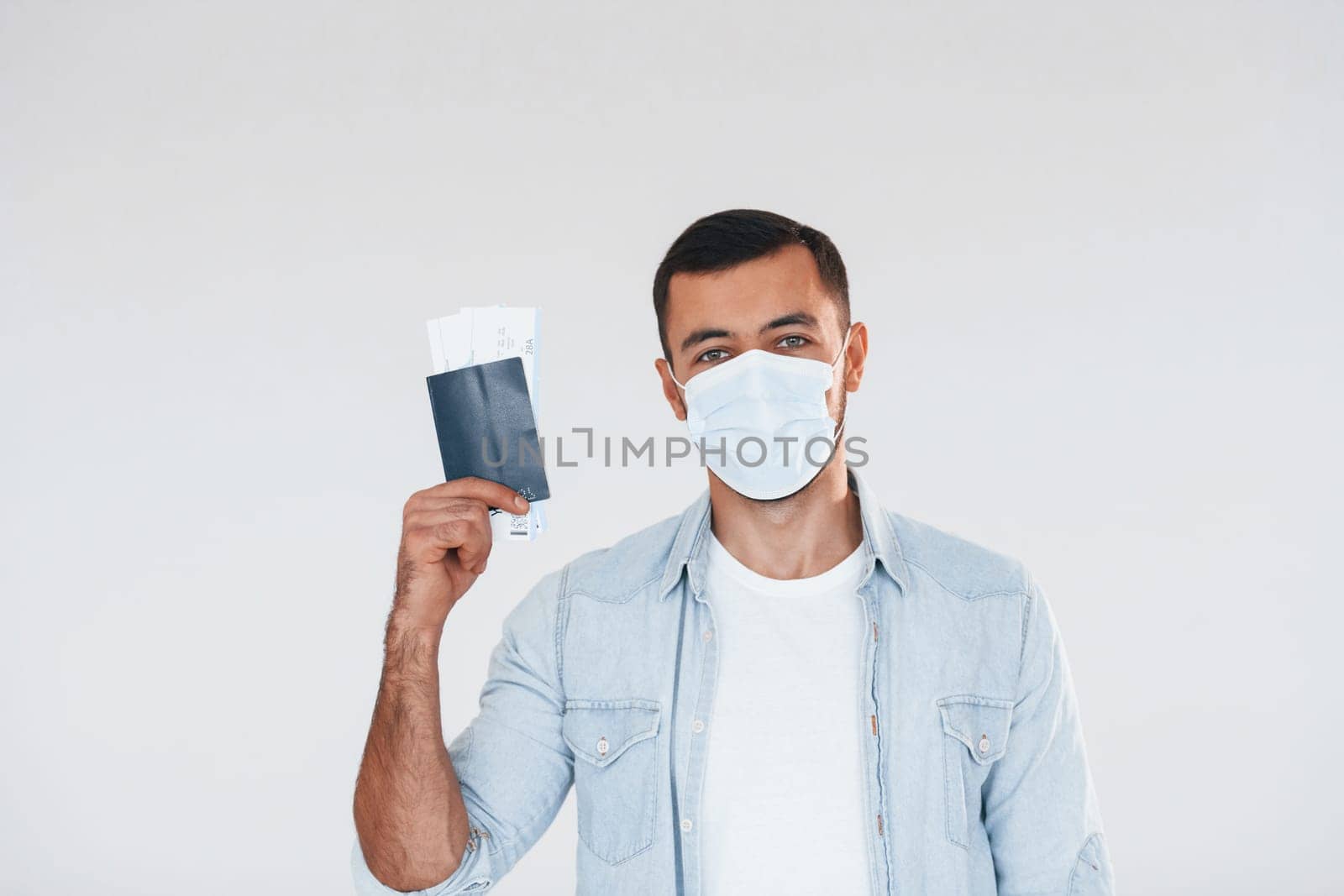 Tourist with ticket. Young handsome man standing indoors against white background.