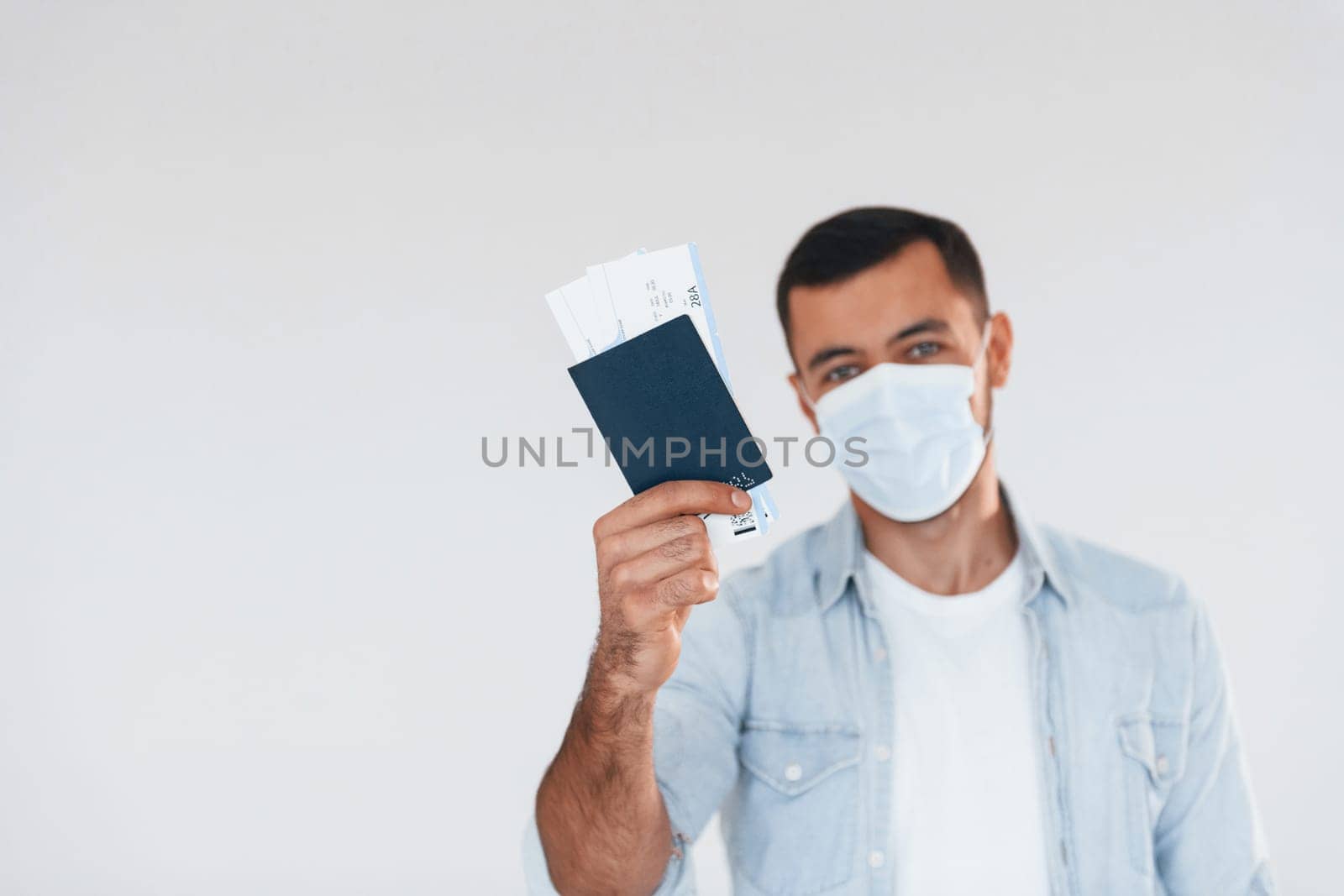 Tourist with ticket. Young handsome man standing indoors against white background.