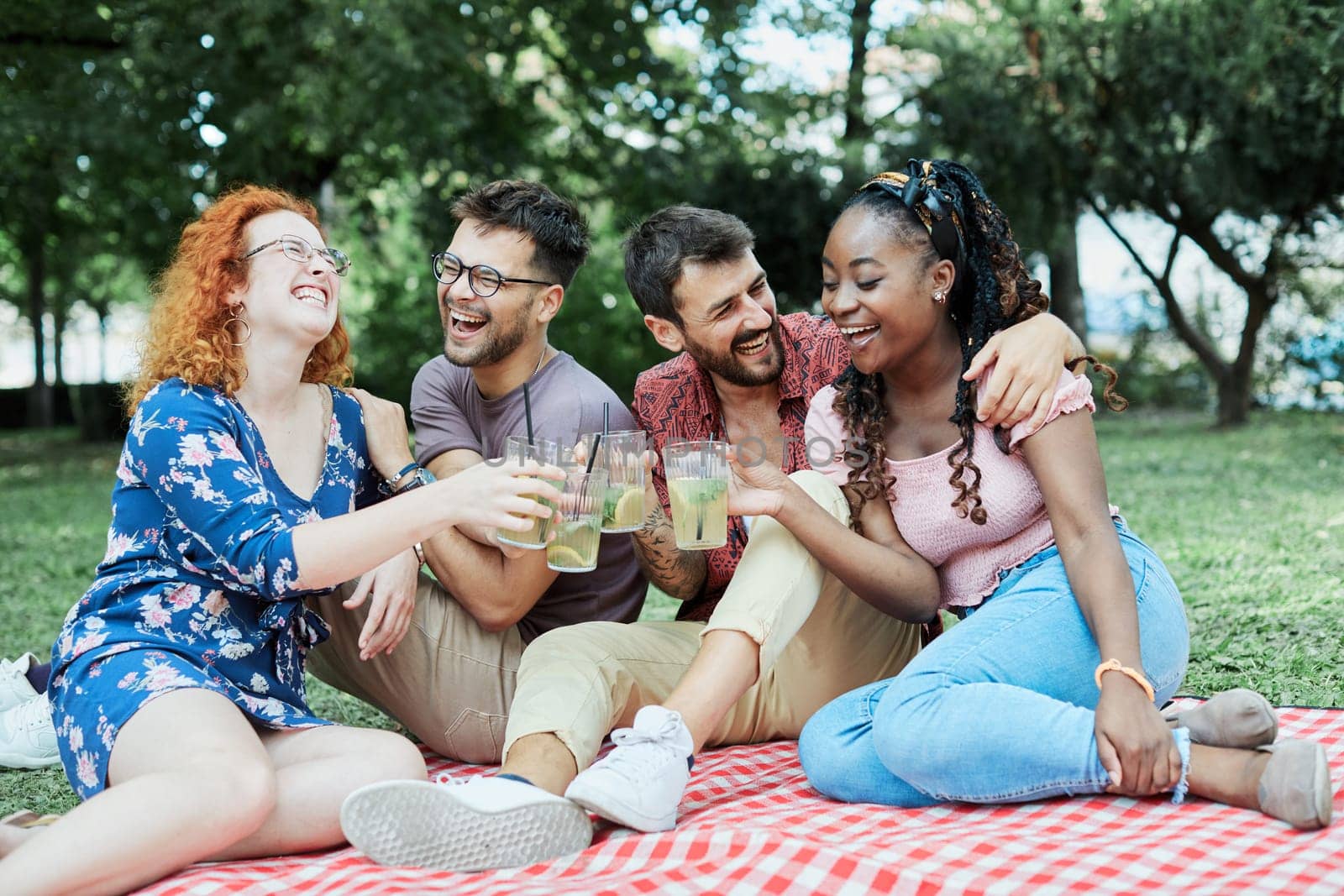 Group of happy young people having a picnic and having a toast with cocktail drinks, having fun together