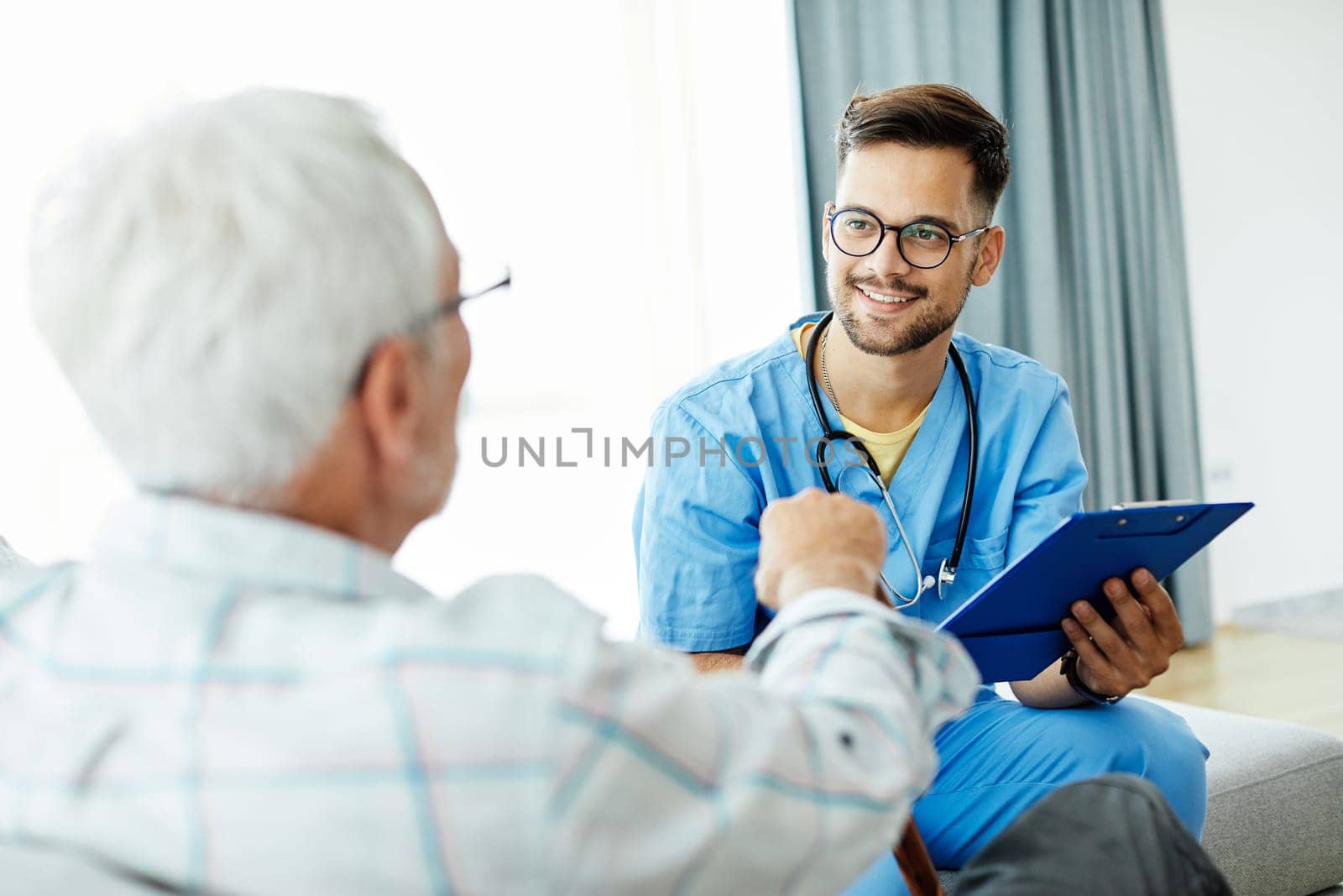 Doctor or male caregiver with senior man holding a cane on sofa at home or nursing home