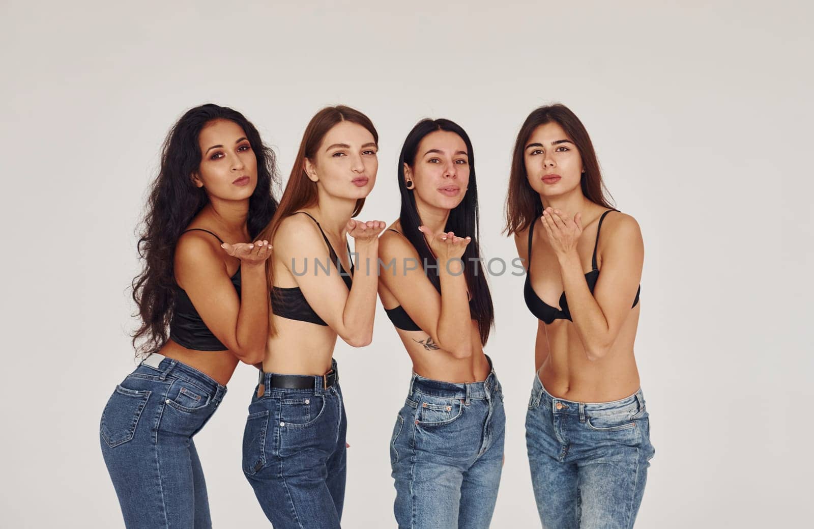 Air kiss. Four young women in lingerie together indoors. White background by Standret