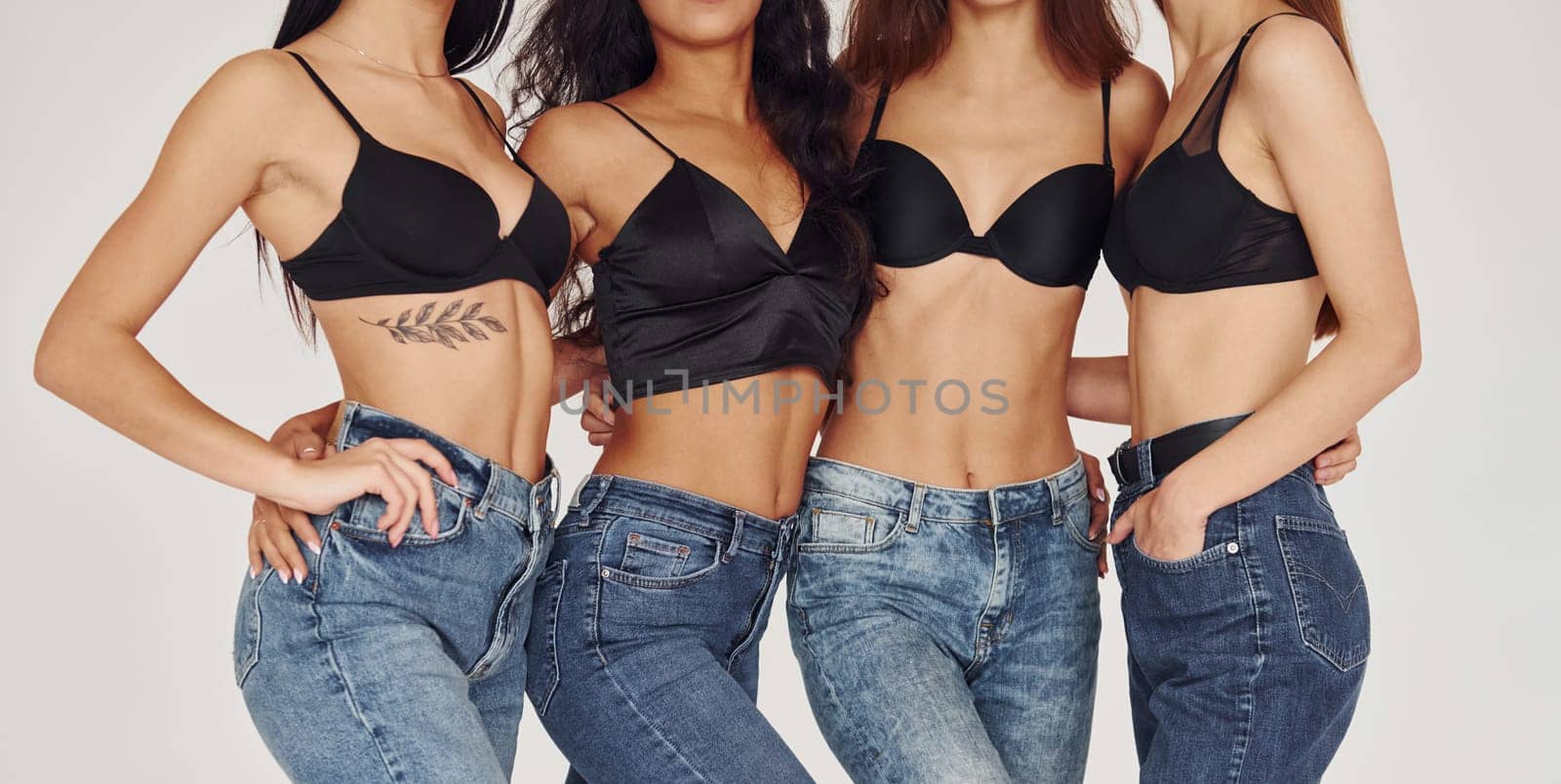 Close up view of bodies. Four young women in lingerie together indoors. White background by Standret