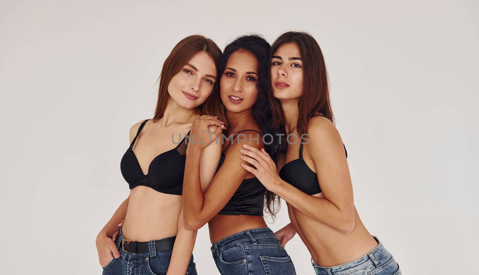 Three young women in lingerie together indoors. White background by Standret