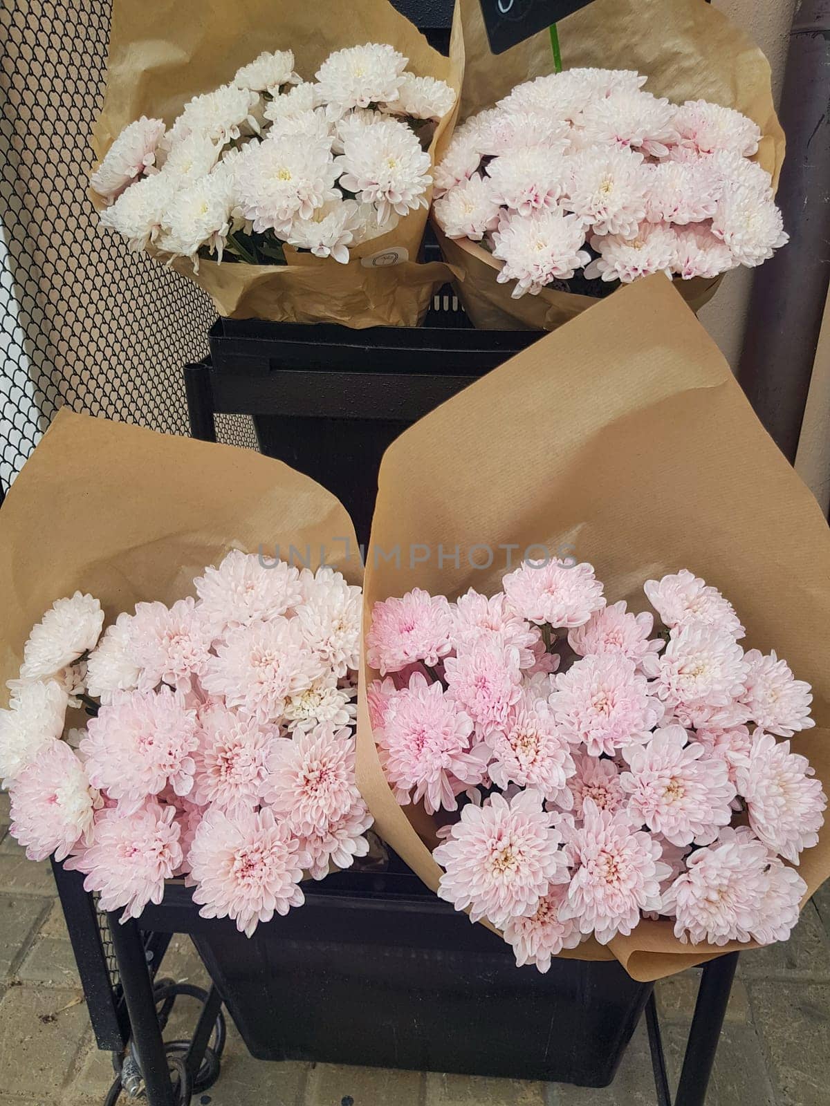 Beautiful gift bouquets of chrysanthemums in brown kraft paper, on the counter of a flower shop, vertical.