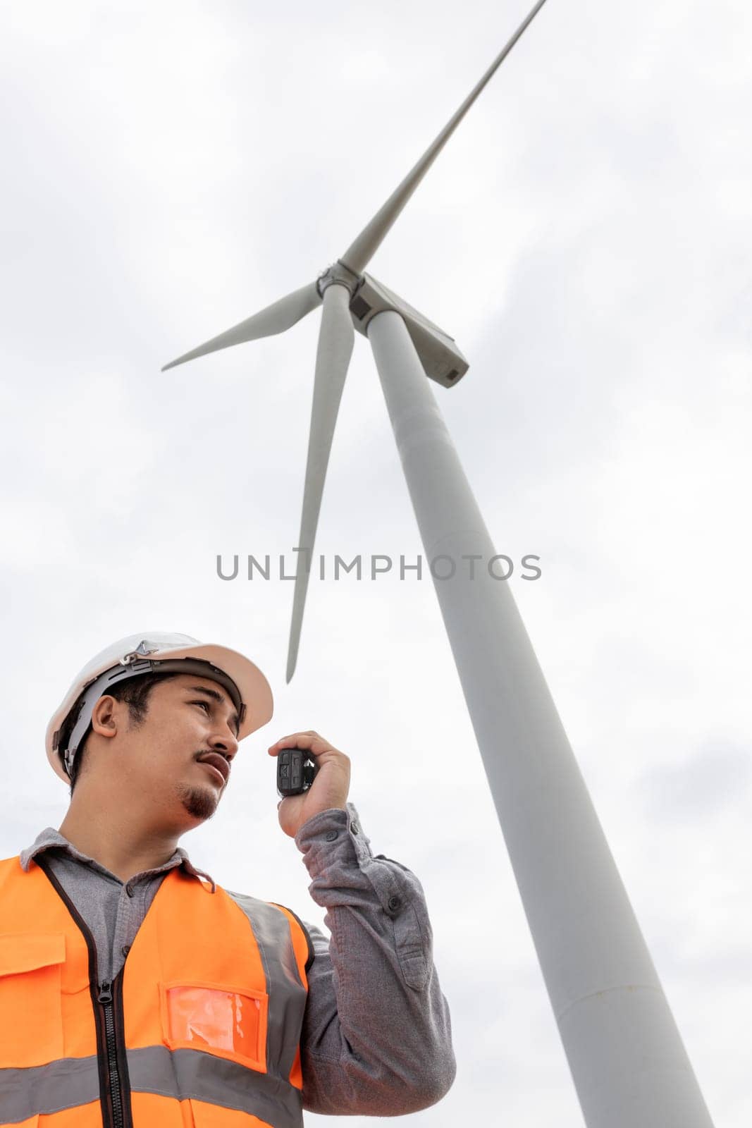 Progressive concept of engineer working in the wind farm atop of the mountain. by biancoblue