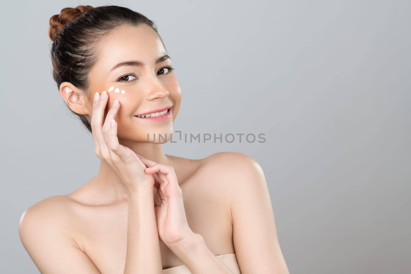 Glamorous woman applying moisturizer cream on her face for perfect skin by biancoblue