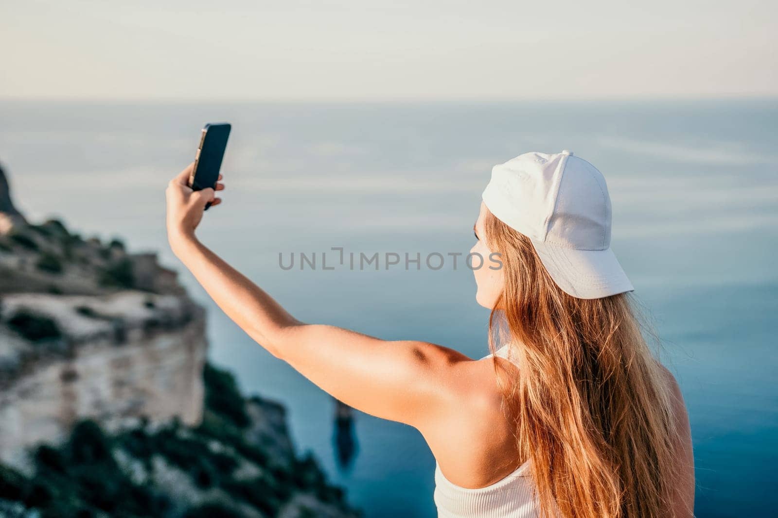 Woman travel sea. Young Happy woman in a long red dress posing on a beach near the sea on background of volcanic rocks, like in Iceland, sharing travel adventure journey