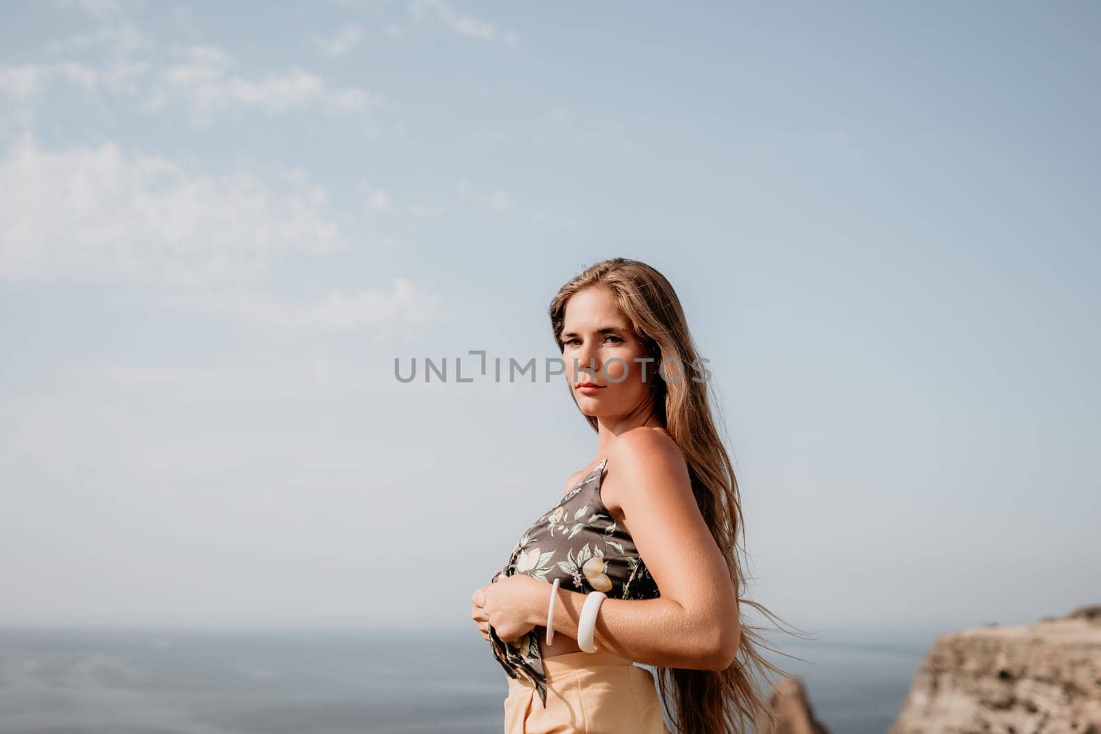 Woman travel sea. Happy tourist taking picture outdoors for memories. Woman traveler looks at the edge of the cliff on the sea bay of mountains, sharing travel adventure journey.