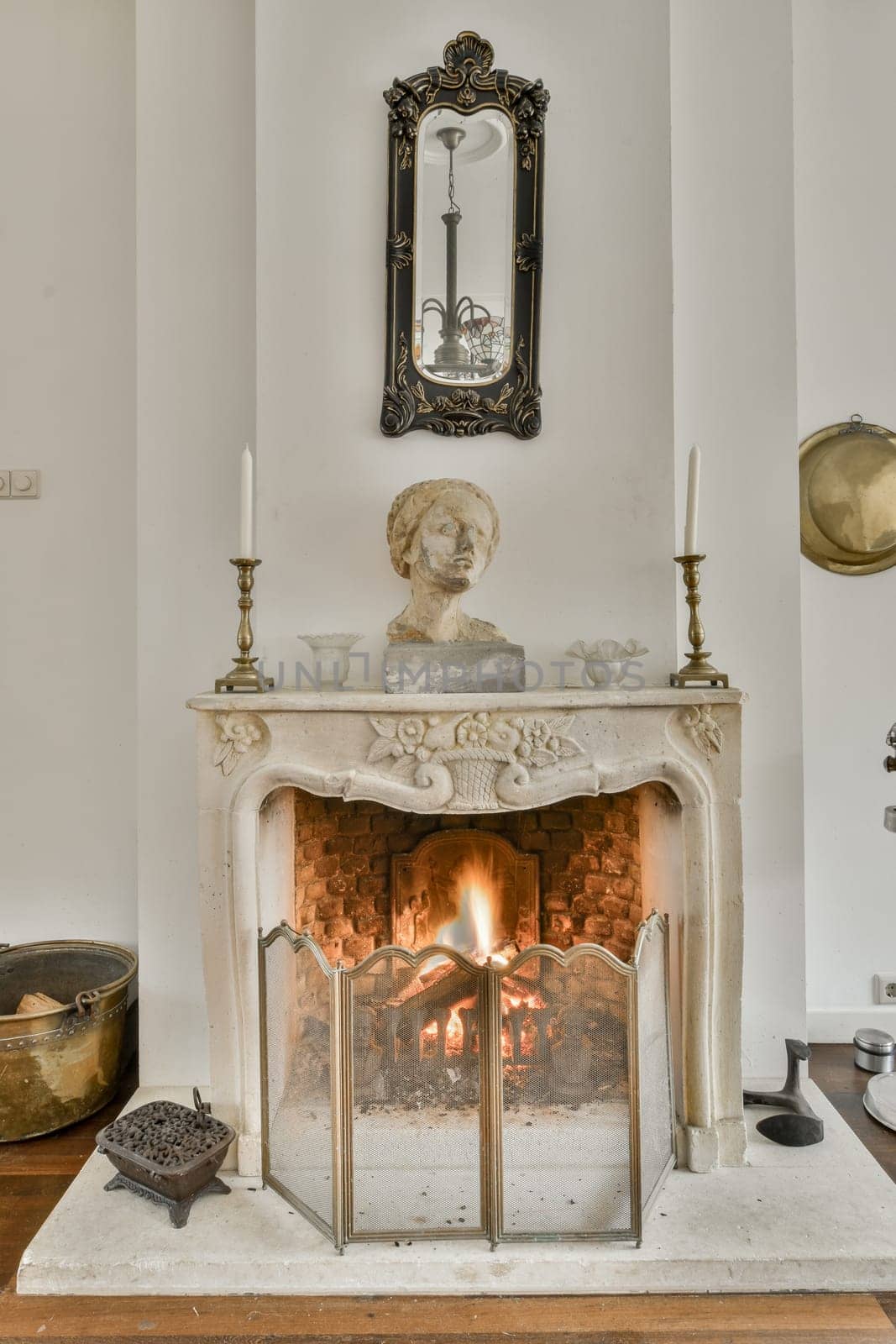 an old fireplace in a room with white walls and wood flooring on the right side, there is a mirror hanging above it