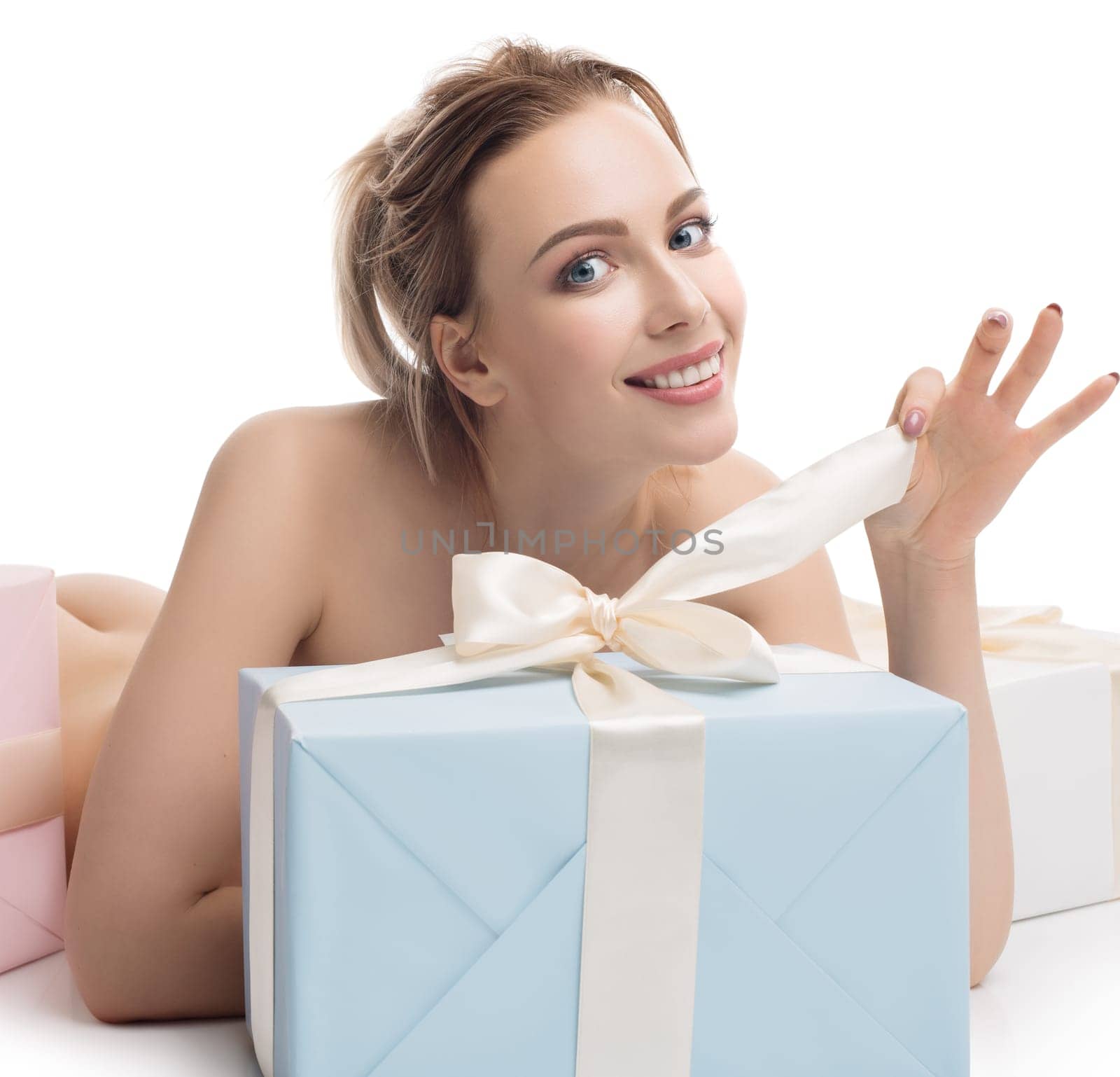 Nude pretty girl and seversal gift boxes tied up with beige ribbions lying on the floor isolated full-length shot on white background