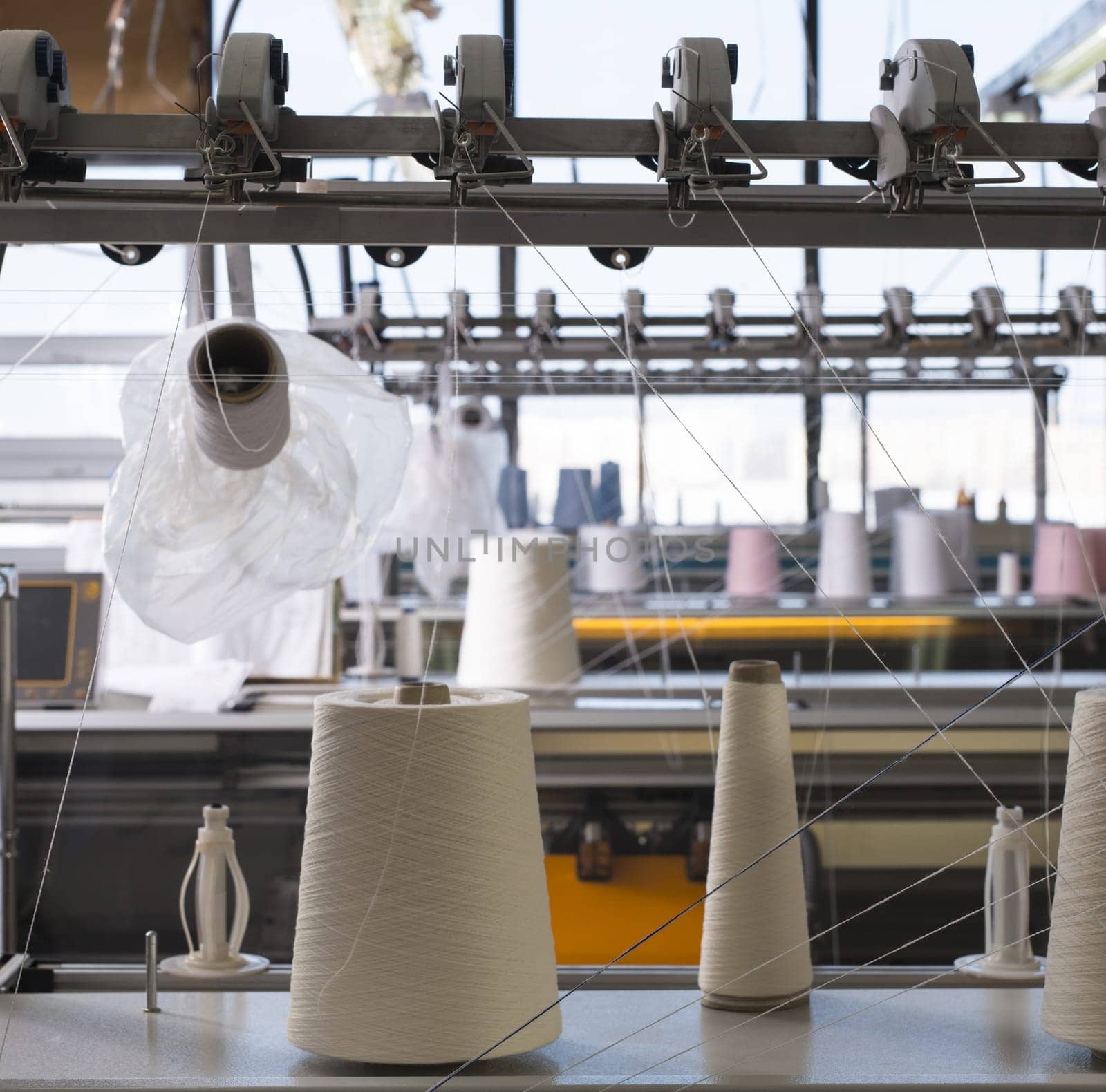 Big spools with white thread at rewinding machine view