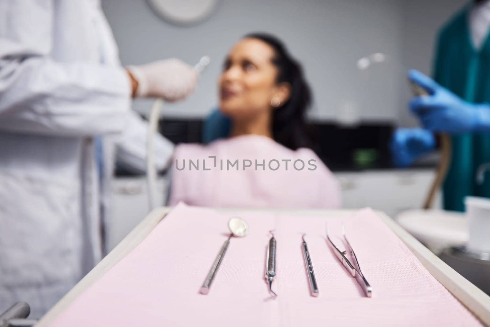 Reporting for dental hygiene duty. a woman having dental work done on her teeth with various tools in the foreground. by YuriArcurs