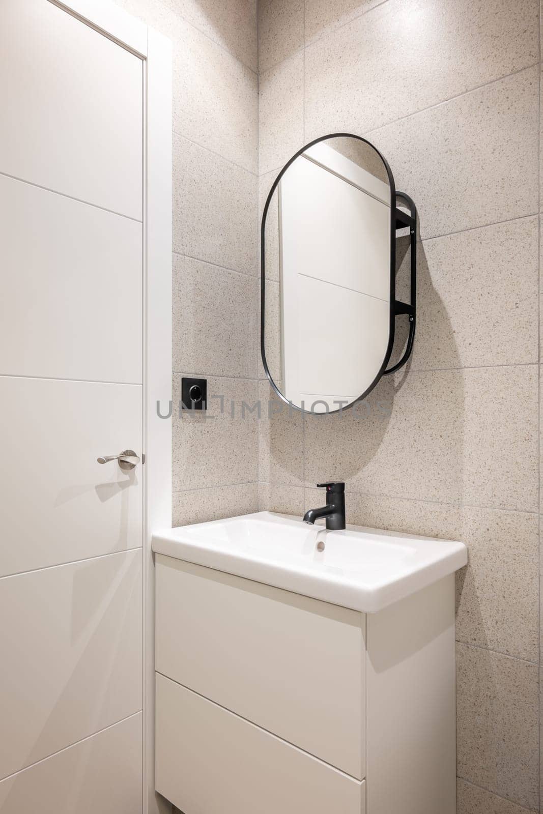 Mirror and cabinet for sink and faucet in a white small bathroom with beige tiles. Concept of a clean small cozy shower room. Bathroom in hotel by apavlin