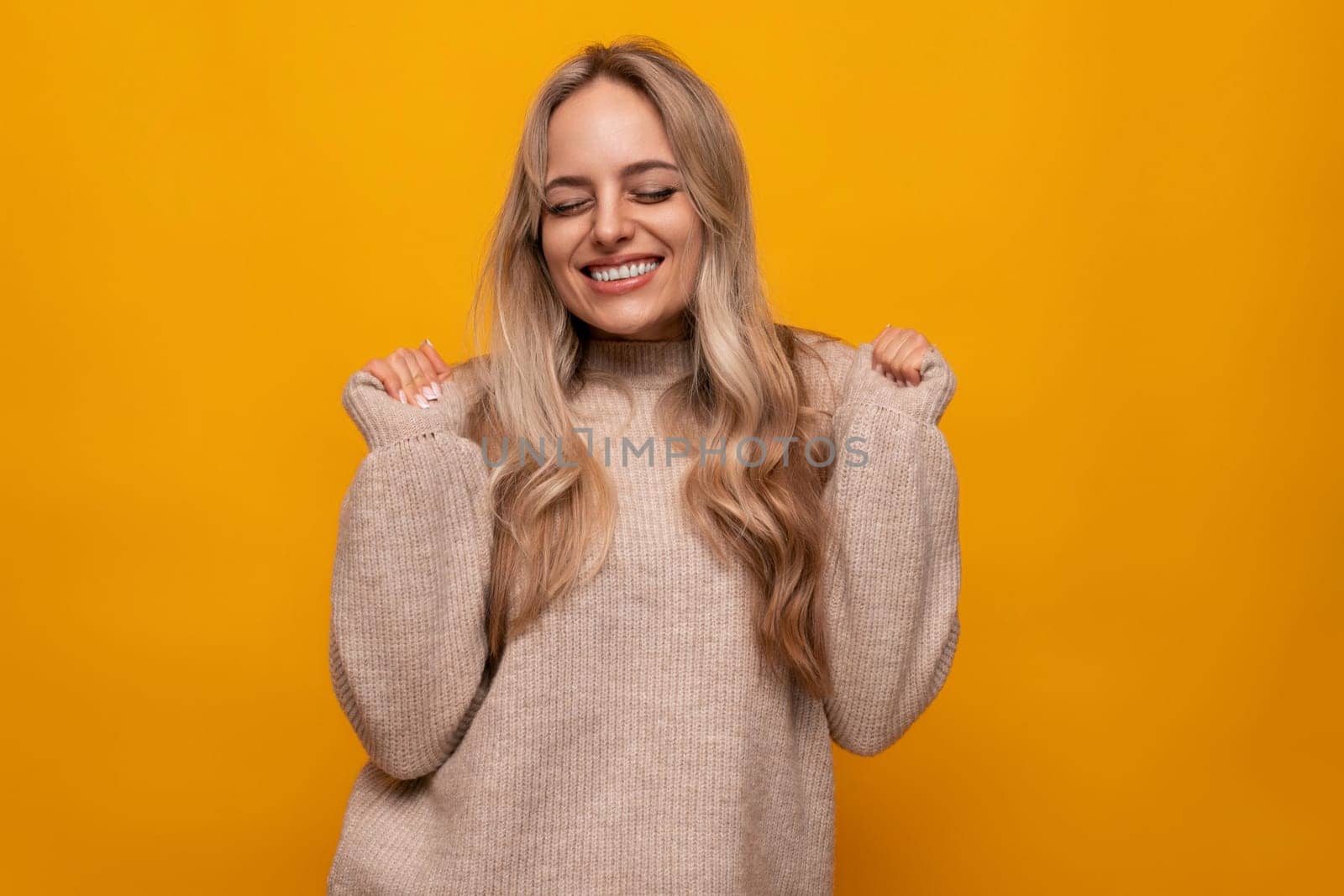 horizontal photo of a blonde young woman screaming on a yellow background.