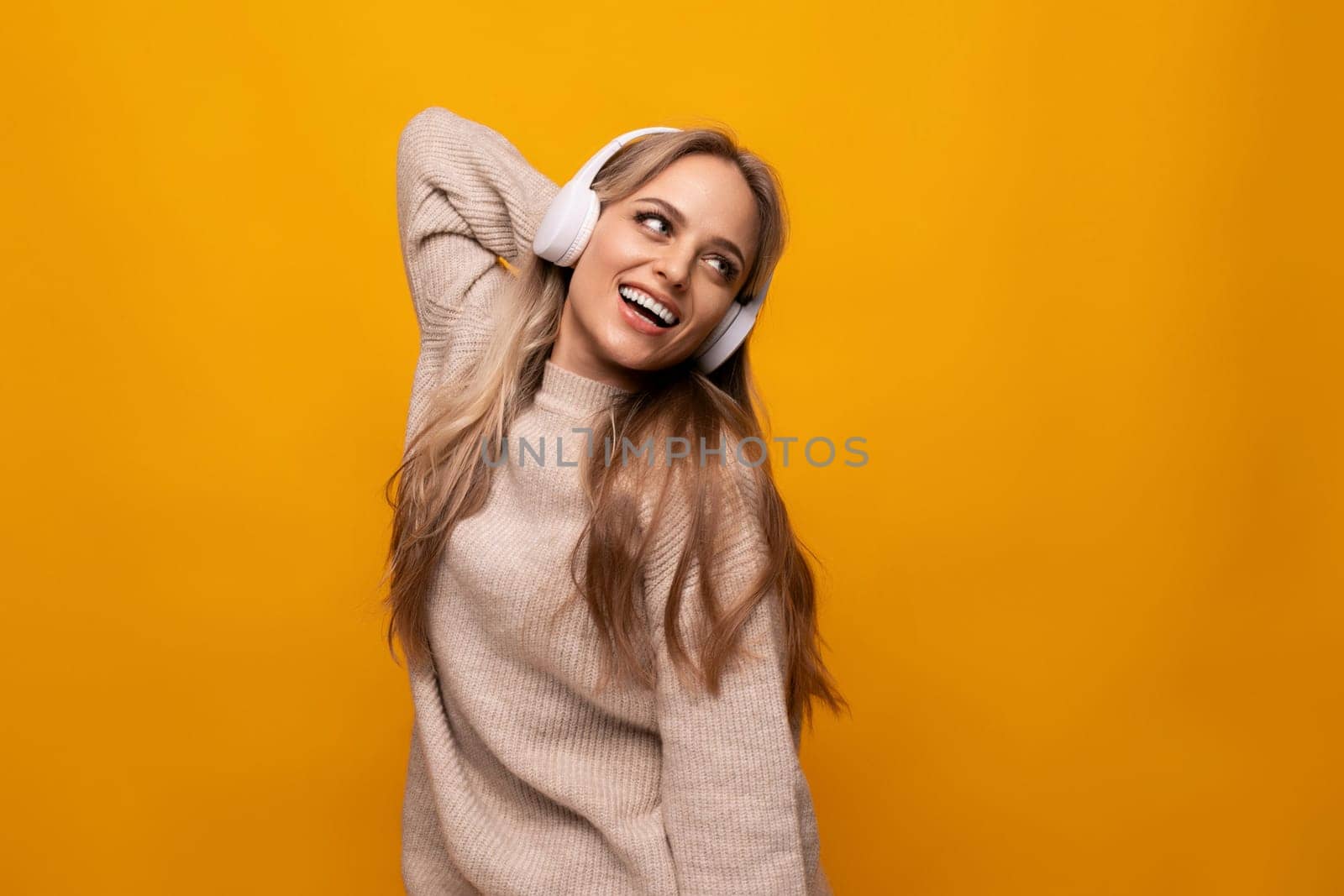 a girl with big headphones listens to her favorite music on a yellow background
