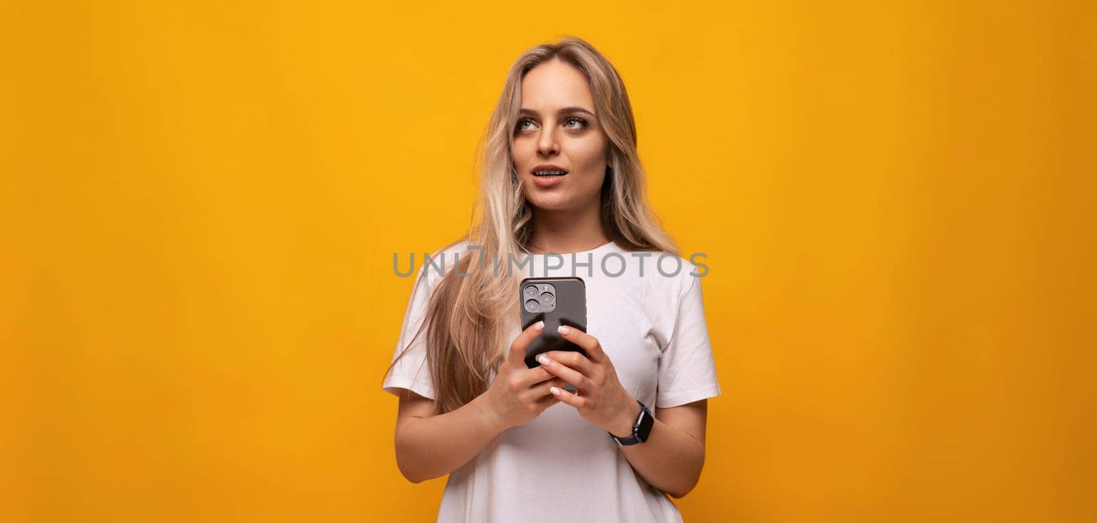 student girl with a phone in her hands on a yellow background.