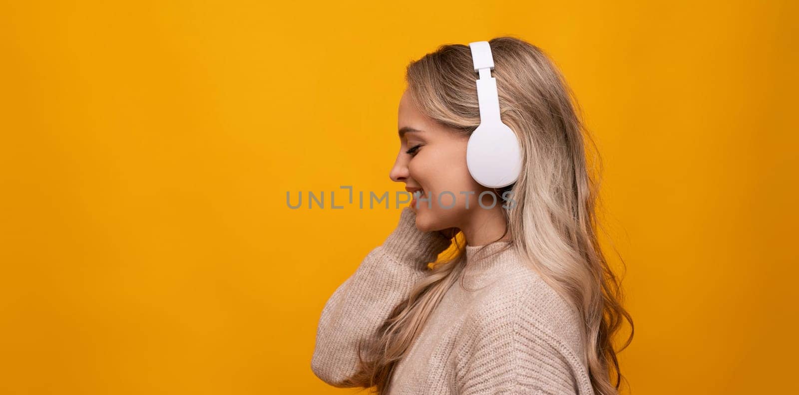 a girl with big headphones listens to her favorite music on a yellow background