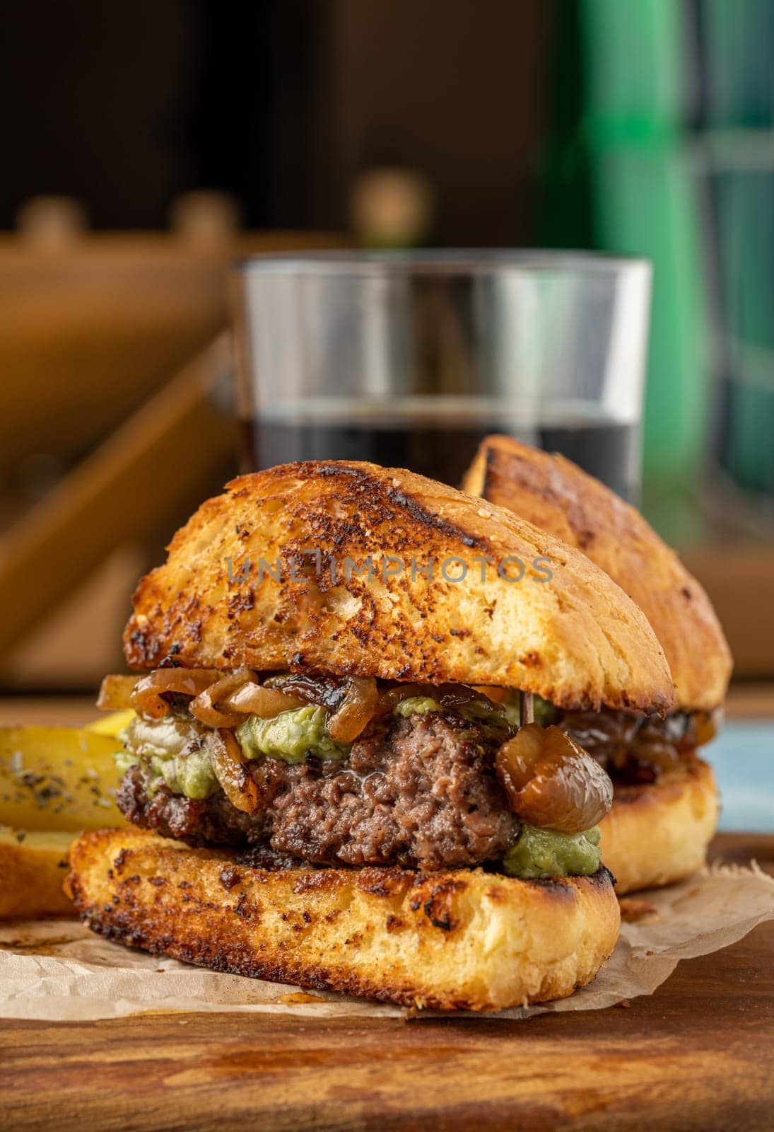 Caramelized onion burger with avocado sauce cut in half, with sauces and french fries on the side