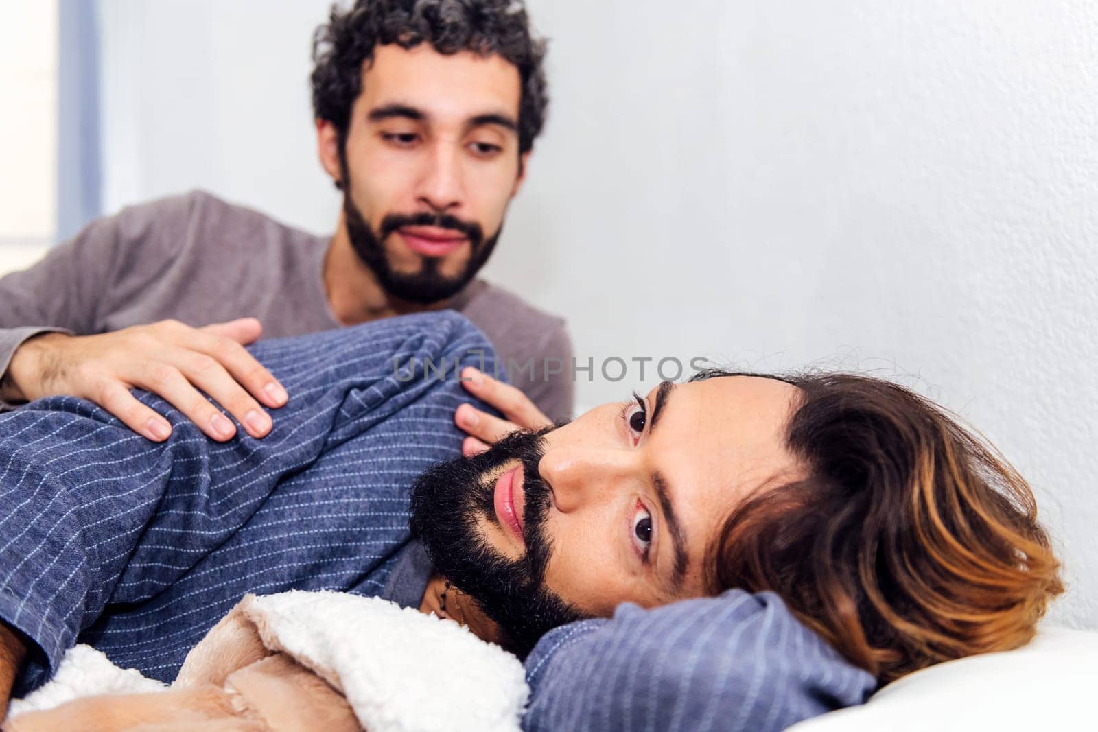 gay male couple together in bed when waking up in the morning, concept of real people lifestyle and love between people of the same sex