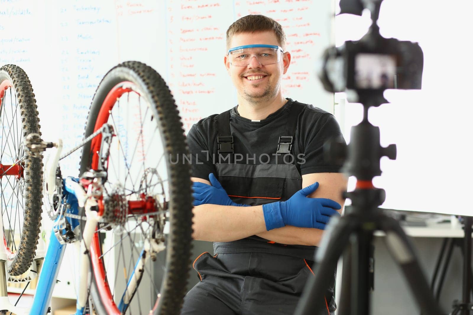 Smiling foreman takes picture of repairing bicycle on camera. Remote bike maintenance on online blog