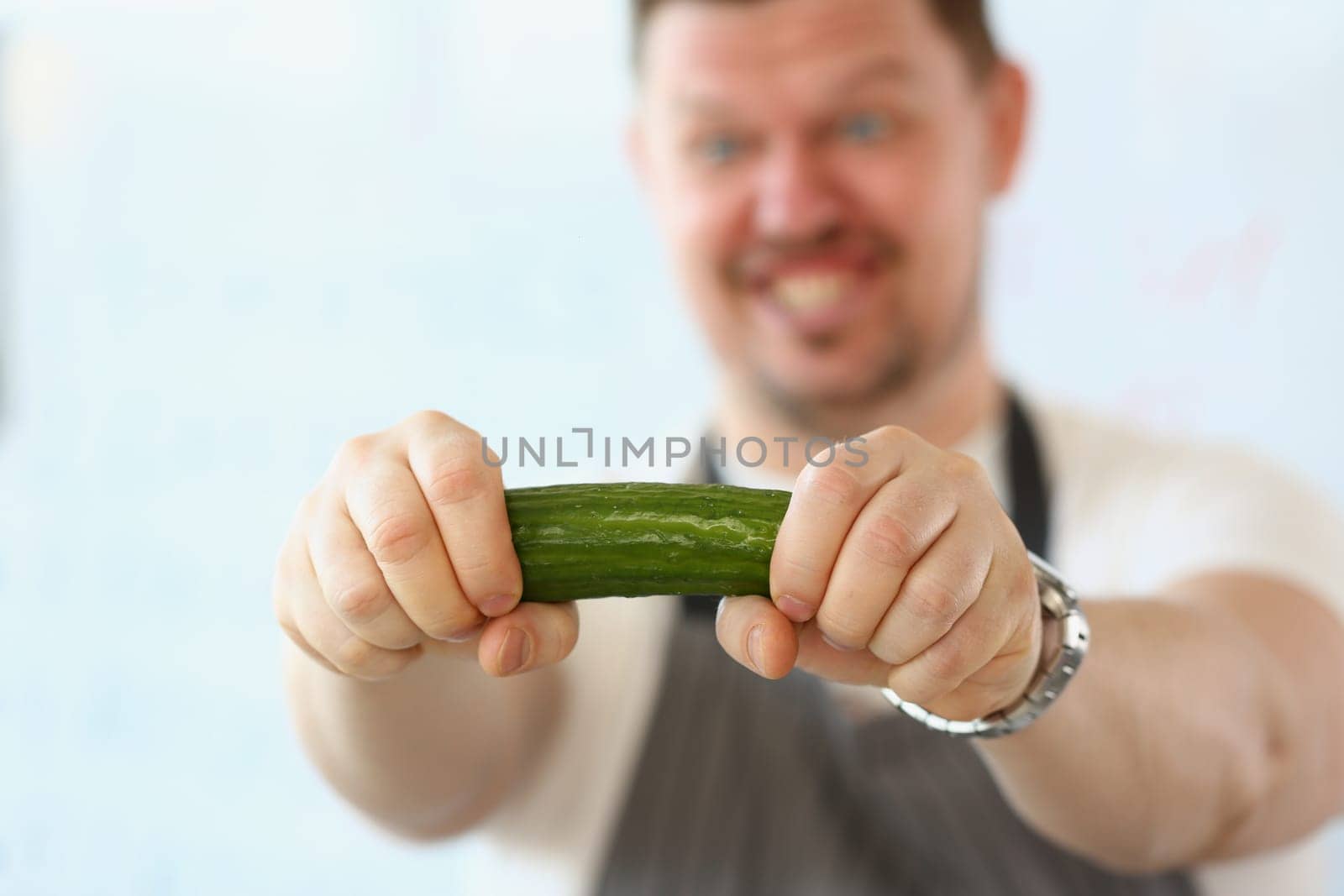 Emotional male cook with cucumber vegetable in hand. Cooking cucumbers in different dishes concept