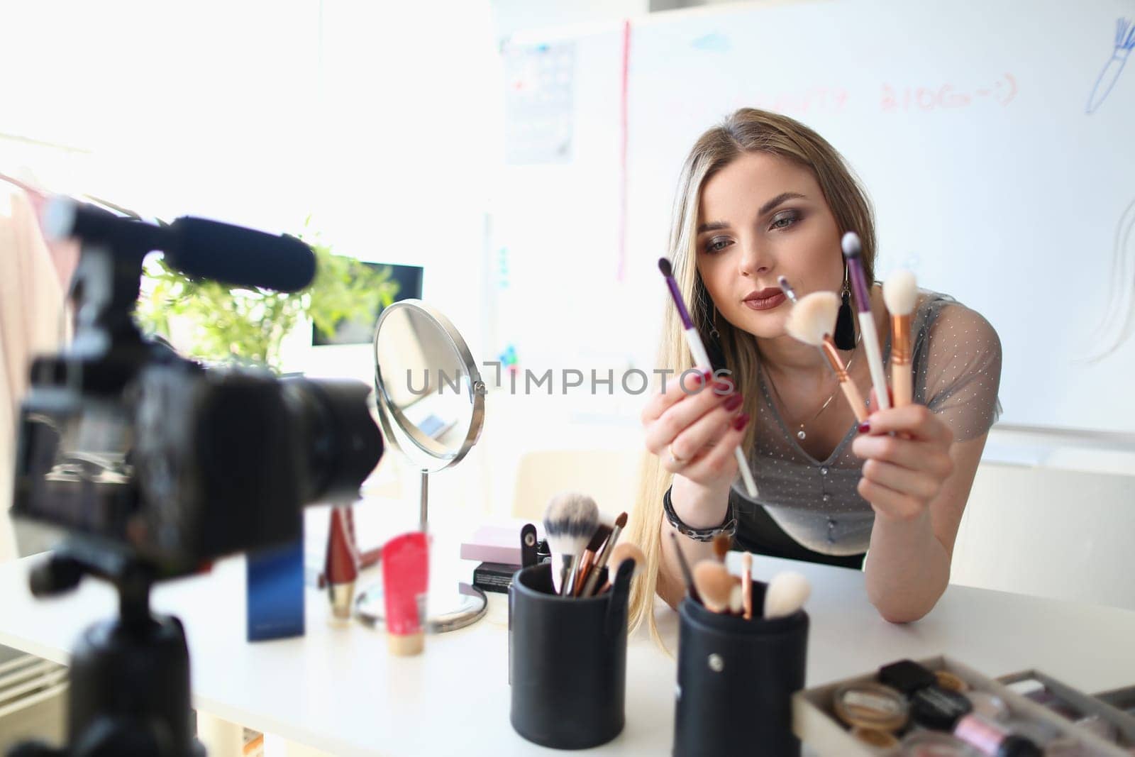 Beauty blogger shoots daily women makeup routine videos on camera. Selection of brushes for applying makeup concept