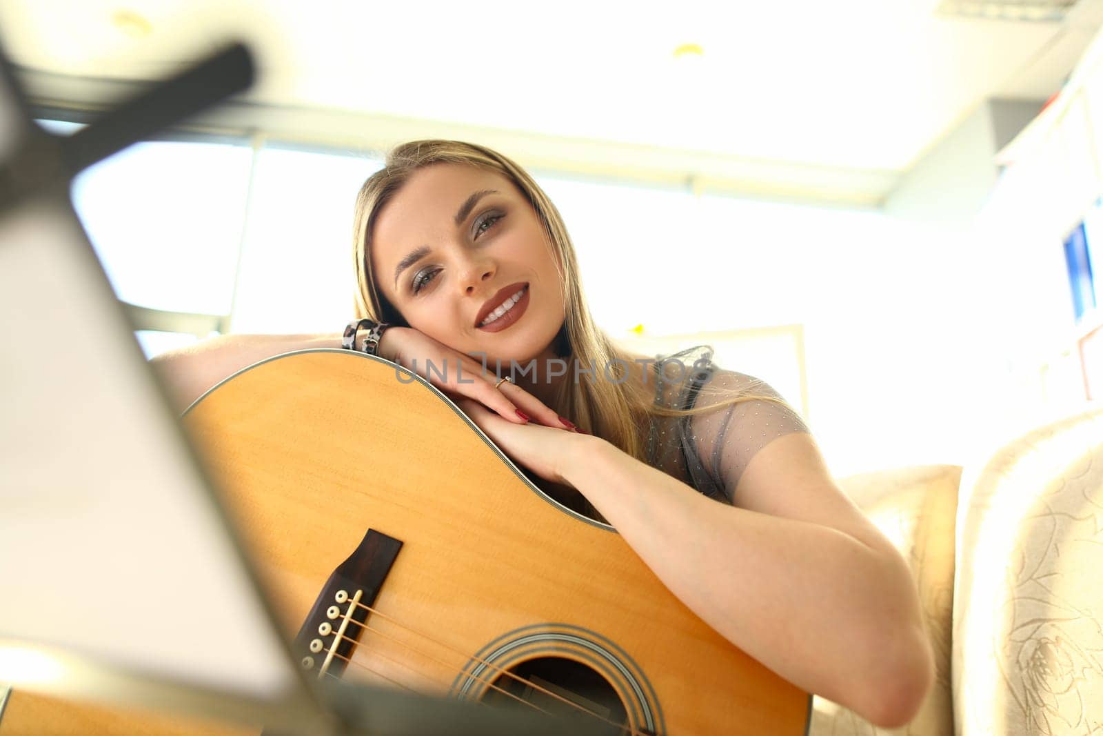 Young beautiful woman playing acoustic guitar at home by kuprevich