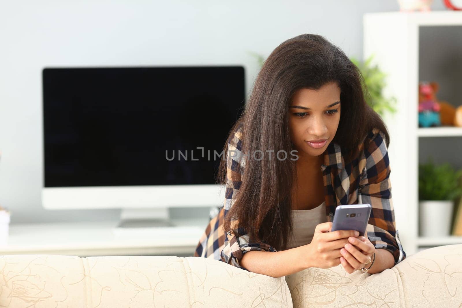 African woman chatting at home using smartphone by kuprevich