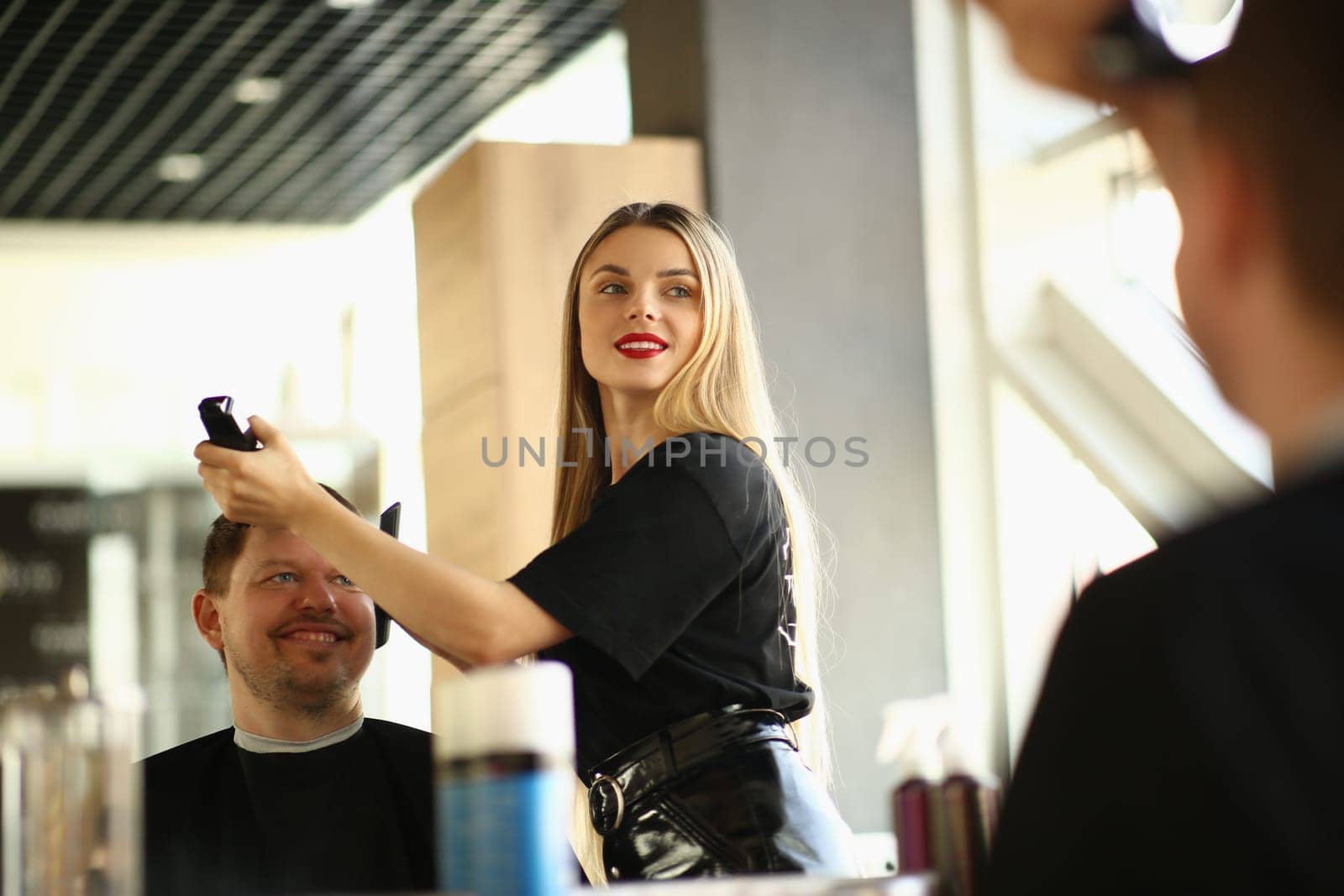 Master barber cuts young man with clipper in beauty salon. Fashionable men's haircuts concept