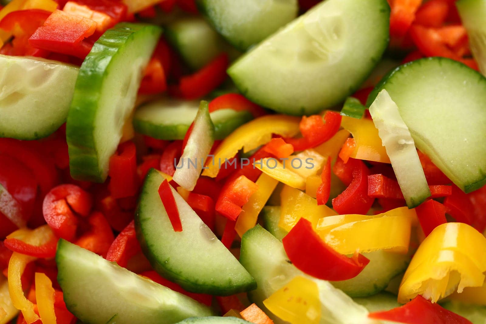 Fresh vegetables cucumbers red yellow peppers sliced in salad by kuprevich
