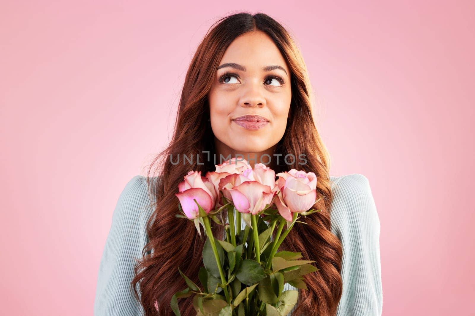 Happy, thinking and female with roses in a studio for valentines day, romance or anniversary. Happiness, smile and young woman model from Mexico with a bouquet of flowers isolated by pink background