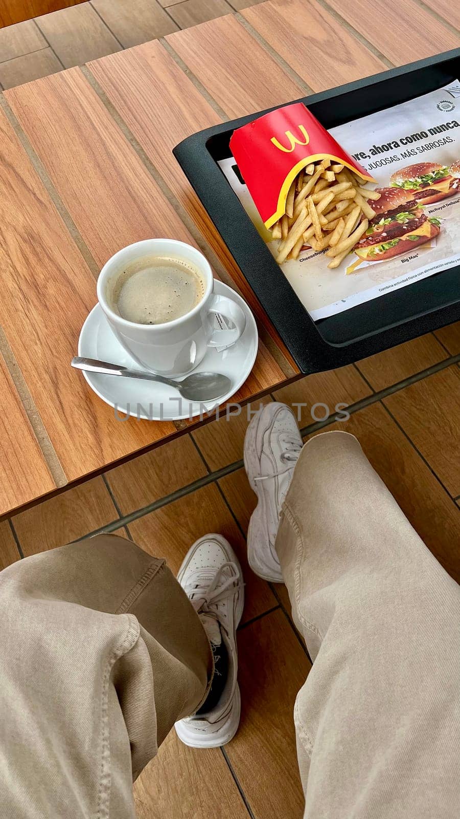 Americano coffee and potato french fries at McDonald's fast food restaurant. Woman eat lunch POV TOP view, close up, vertical, flatly