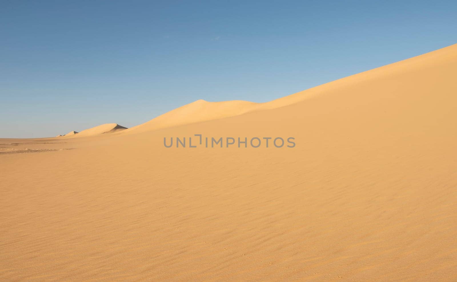 Landscape scenic view of desolate barren western desert in Egypt with Karaween large sand dunes against blue sky background