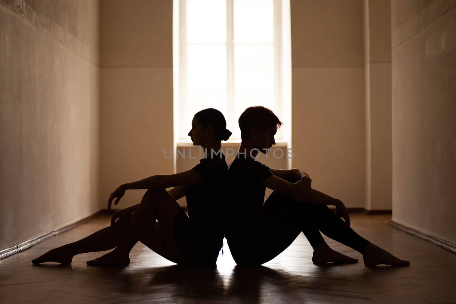 Male and female dancers sitting on the floor of the corridor of the theatre by VitaliiPetrushenko