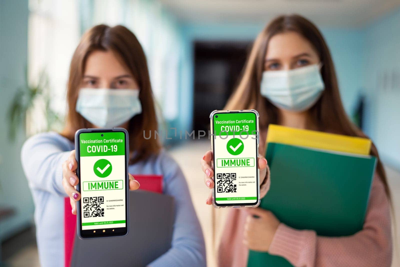 Two students showing screens of phones with digital certificates of successful vaccination