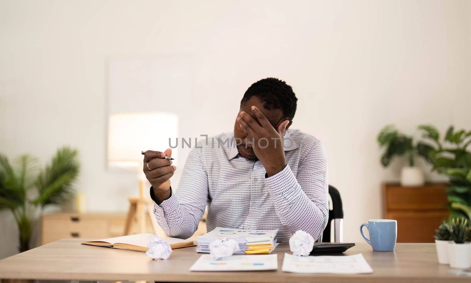 Concentrated business african american man working from home, sitting at work desk, using laptop, looking at laptop thoughtfully, hands near face, thinking about financial business plan or new startup..