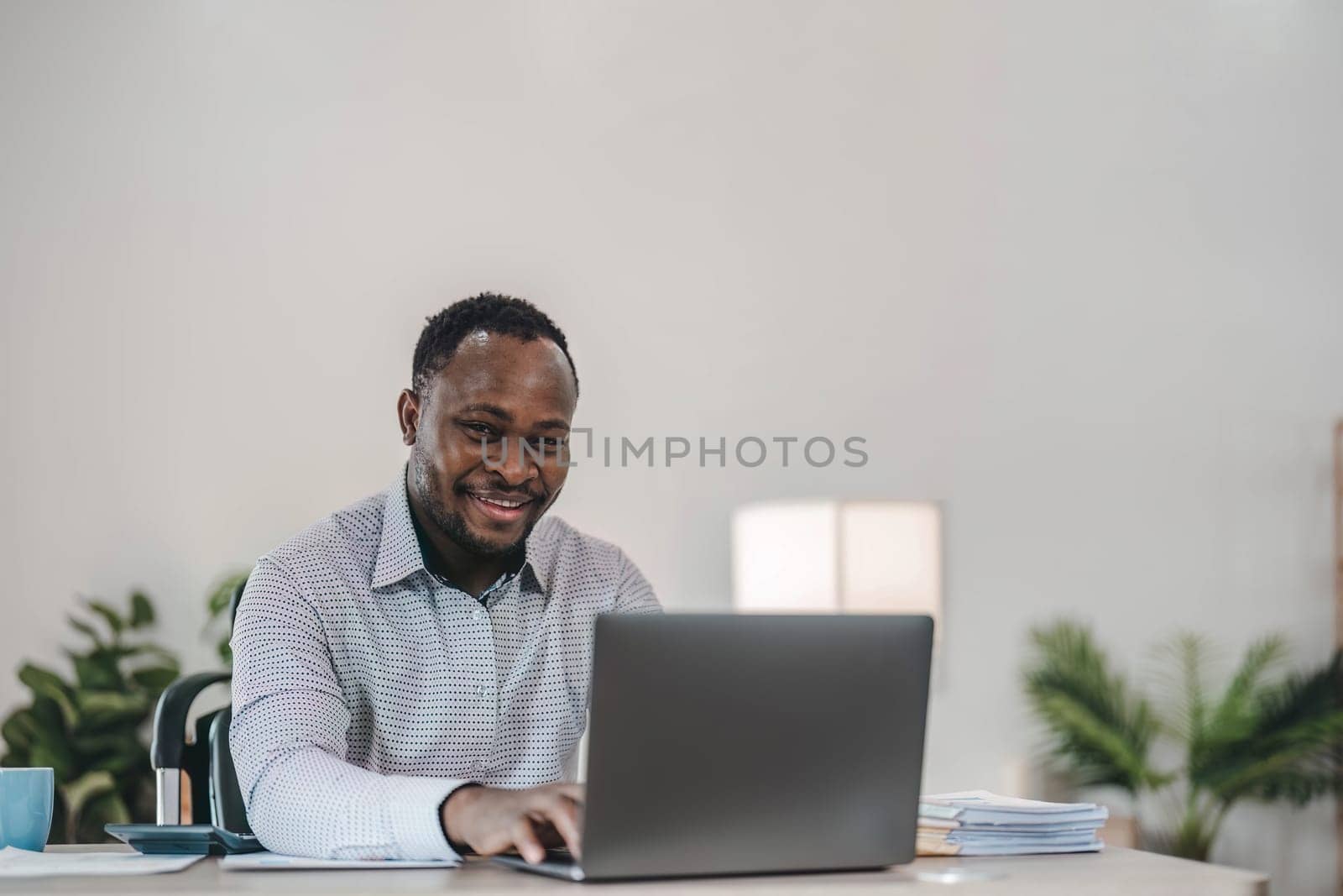 Professional male economist searches needed information on portable computer, happy to recieve high net profit, spends important banking operation. Black male trader analyzes financial market..