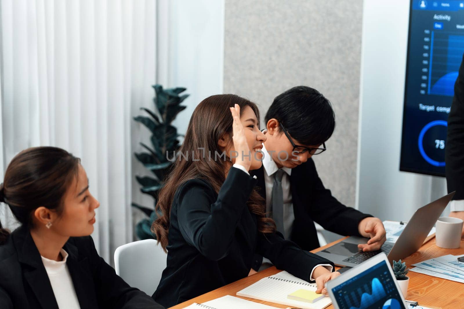 Harmony group businesspeople in meeting room during presentation with dashboard BI financial data displayed on screen, motivated employee raising hand asking question as productive teamwork concept.