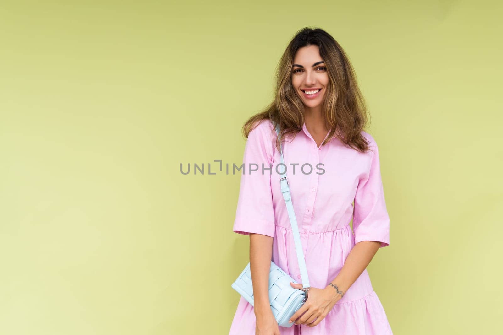 Young woman in casual pink summer cotton dress wear isolated on green background holding cute blue shoulder bag happy big smile by kroshka_nastya