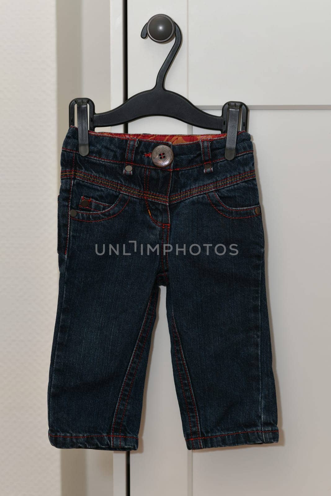 A baby trousers hang on a hanger
