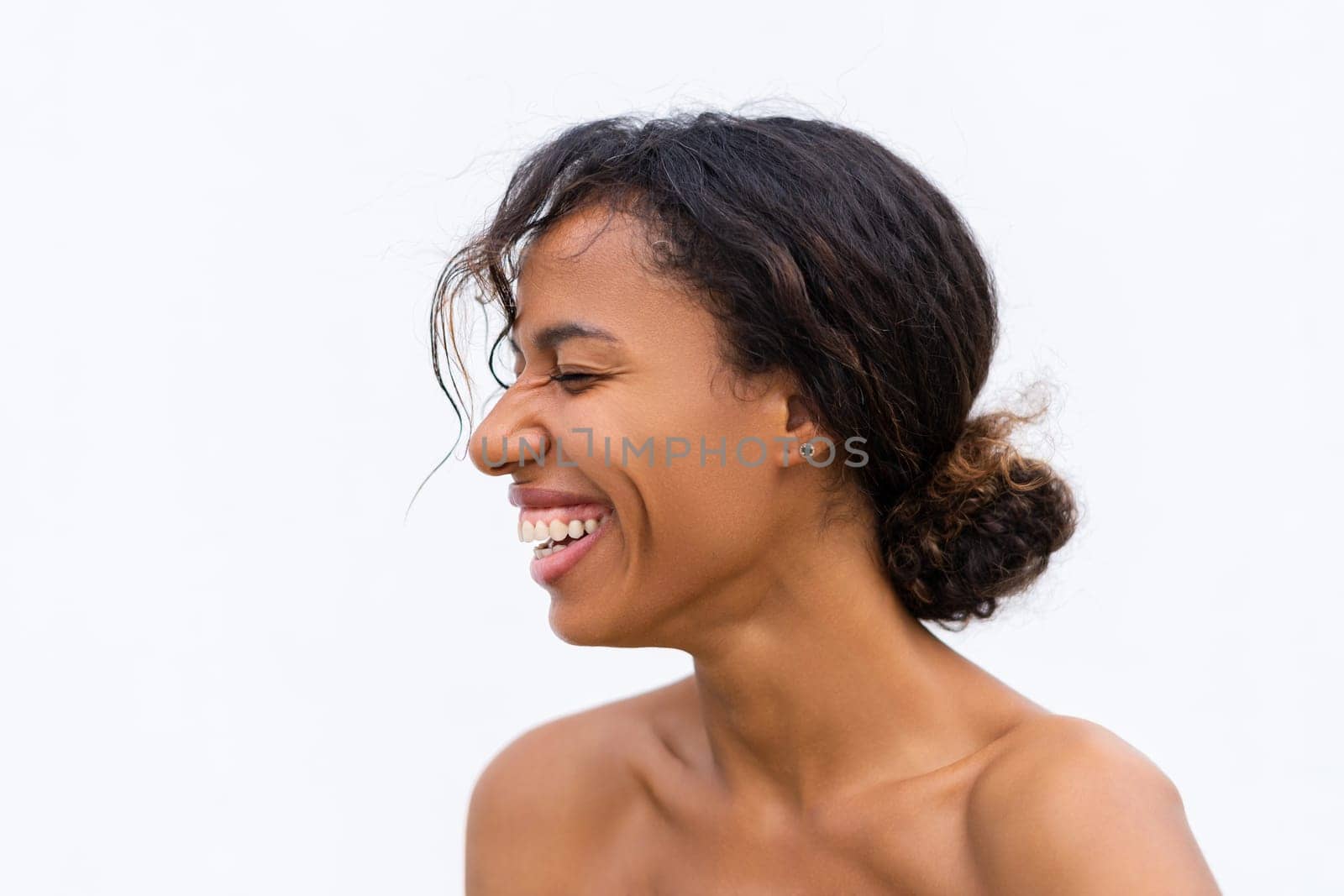 Beauty portrait of young topless african american woman with bare shoulders on white background with perfect skin and natural makeup positive laughing by kroshka_nastya