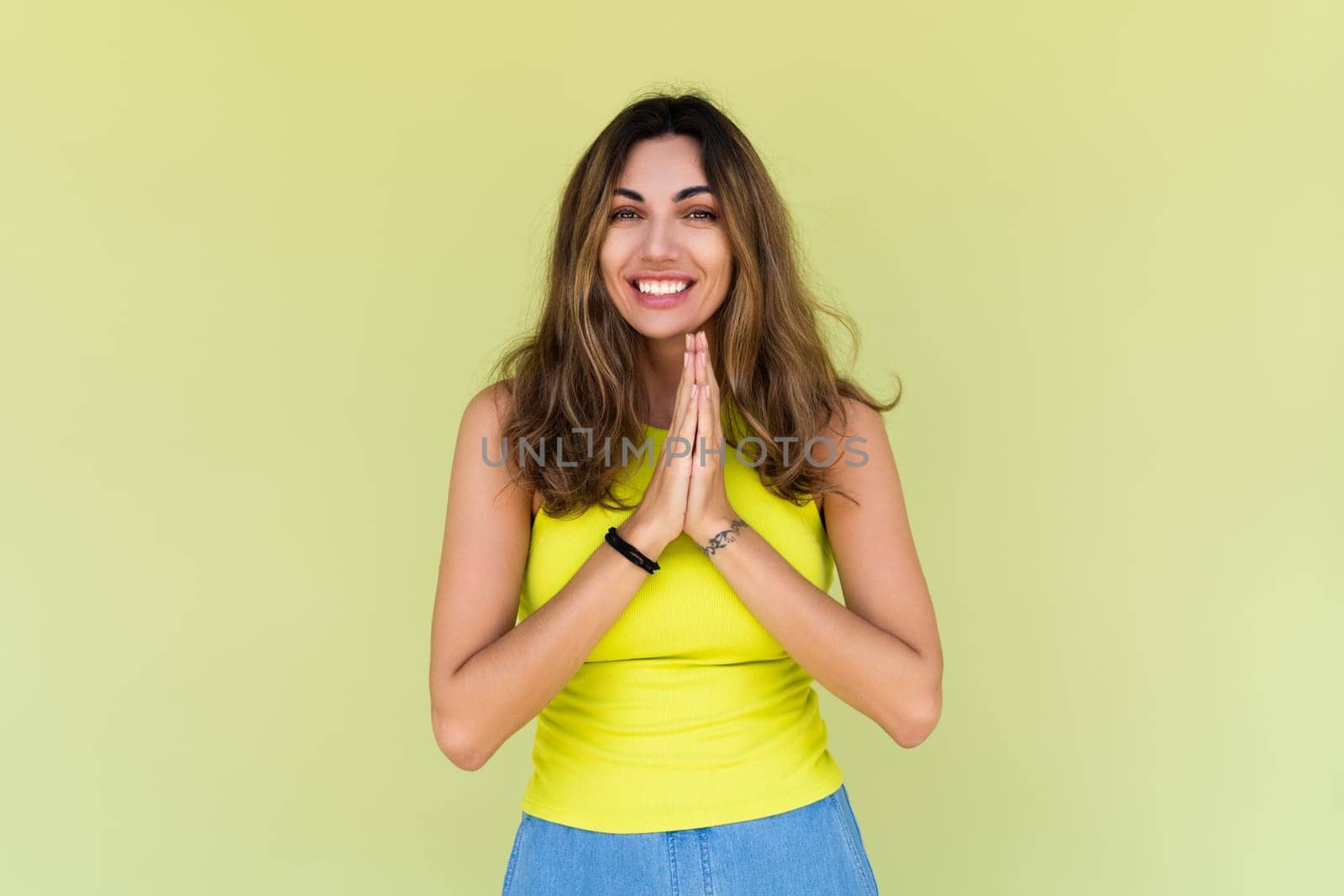 Young brunette in casual wear isolated on green background happy look to camera smile excited