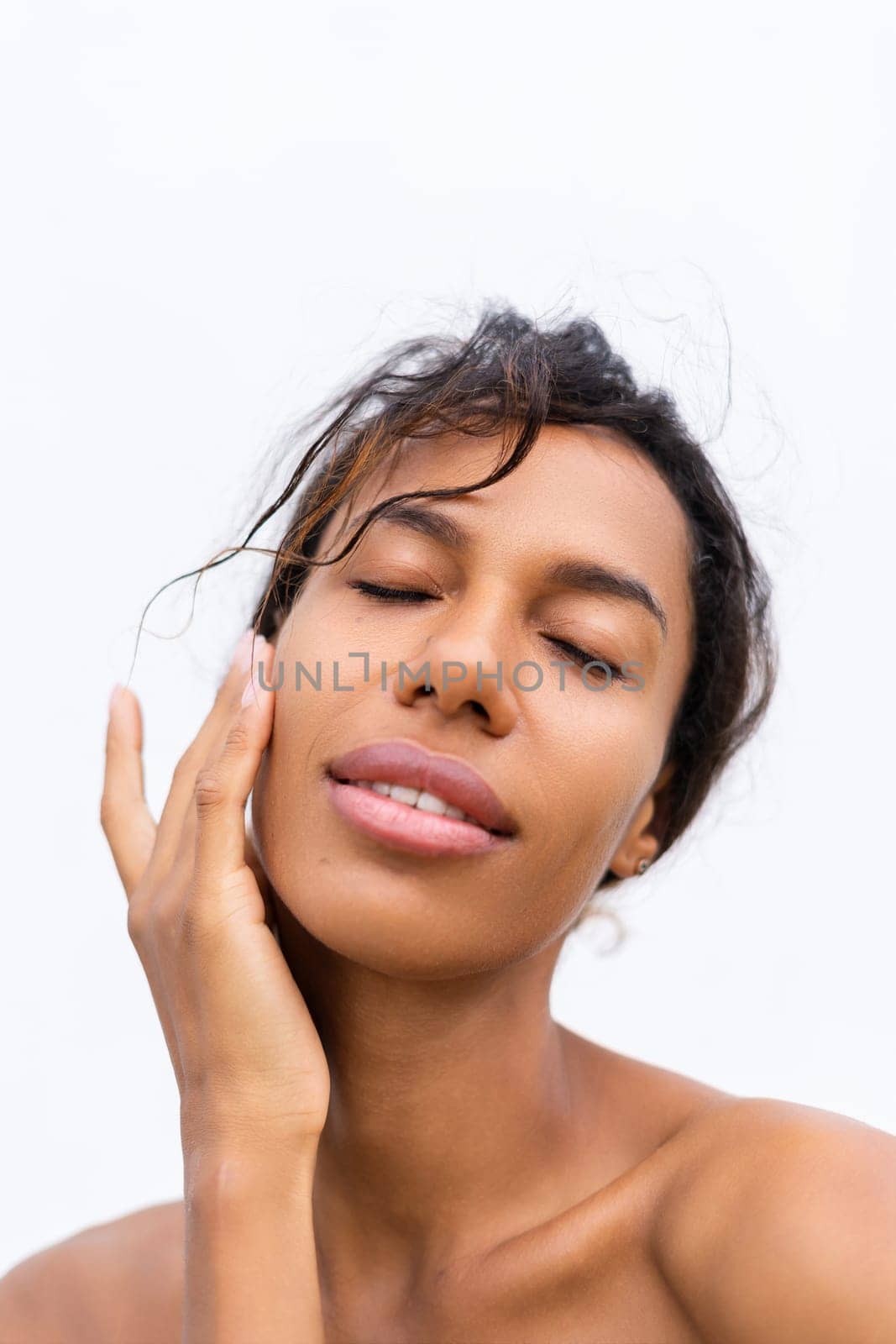 Beauty portrait of young topless african american woman with bare shoulders on white background with perfect skin and natural makeup positive
