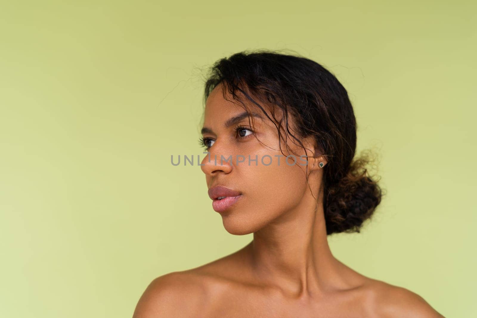 Beauty portrait of young topless african american woman with bare shoulders on green background with perfect skin and natural makeup by kroshka_nastya