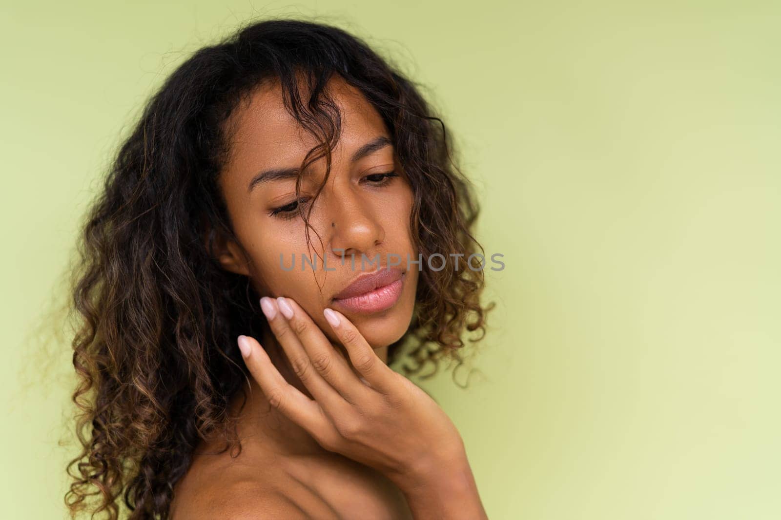 Beauty portrait of young topless african american woman with bare shoulders on green background with perfect skin and natural makeup by kroshka_nastya